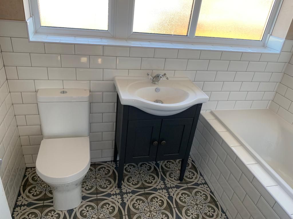 En-suite with a gloss-black vanity, white basin, backlit mirror and a black-framed walk-in shower, bedroom reflected in the glass