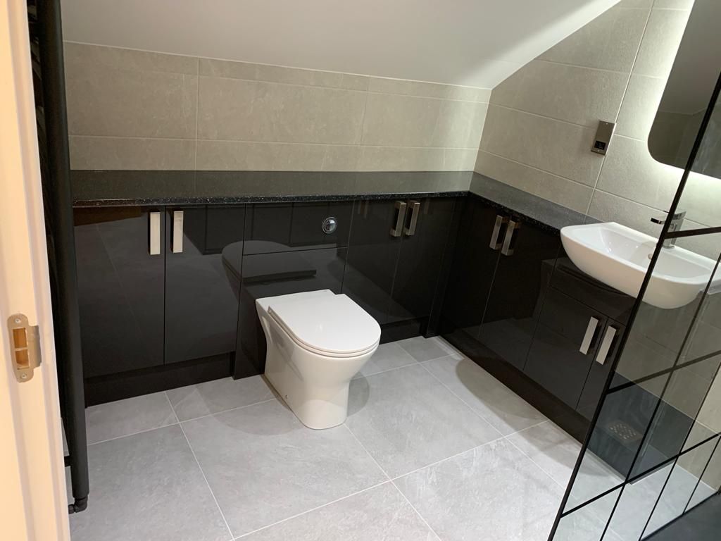 Stone-effect bathroom with a freestanding bath, curved quadrant shower enclosure and white vanity unit