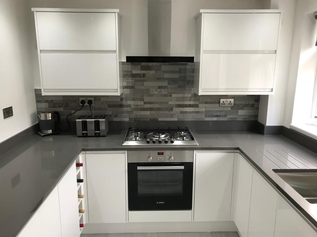 Grey shaker kitchen with white quartz tops, a stainless range cooker, Belfast sink and navy island with mustard bar stools