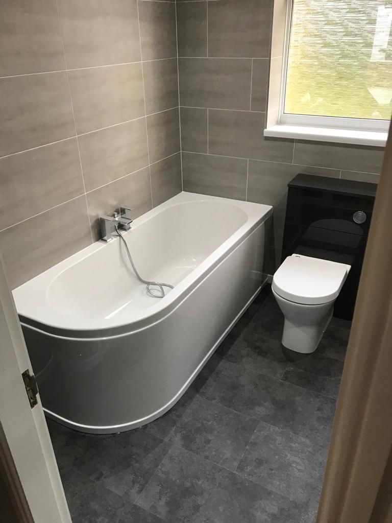 Loft shower room with grey brick-effect tiling, a black slate shower tray, glass screen and black towel radiator