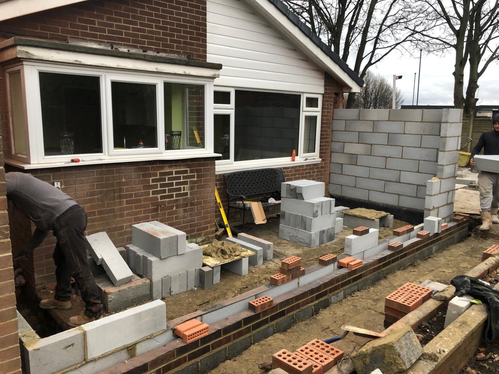 Parapet brickwork opened up on scaffolding showing the inner cavity and a salt-glazed pipe during a roof-line rebuild