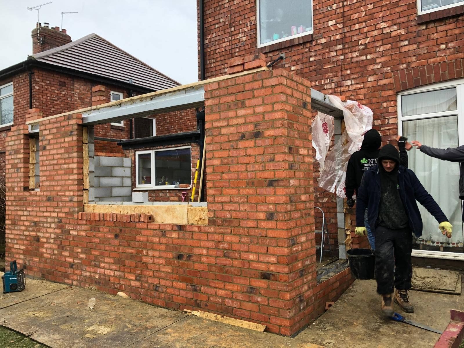 Two-storey rear elevation with a large structural opening cut through the brickwork and supported on steel, glazed door visible inside